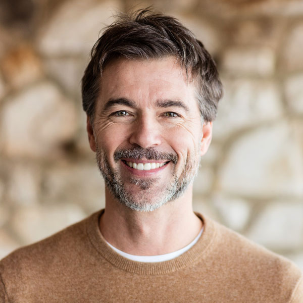 Lightly bearded man in a sweater happily smiling