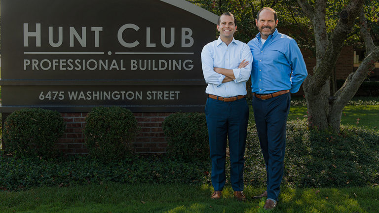 Dr. Bradley Rule and Dr. Scott Rule standing in Front of the Hunt Club Sign and smiling