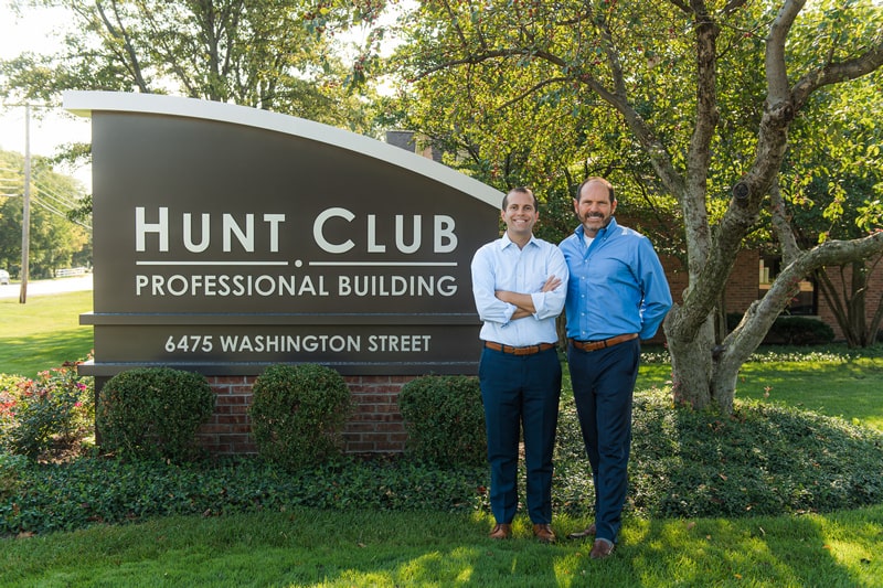 Dr. Bradley Rule and Dr. Scott Rule standing in Front of the Hunt Club Sign and smiling