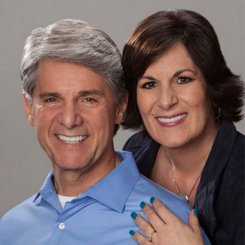 Middle-aged couple hugging and happily smiling on a grey studio background