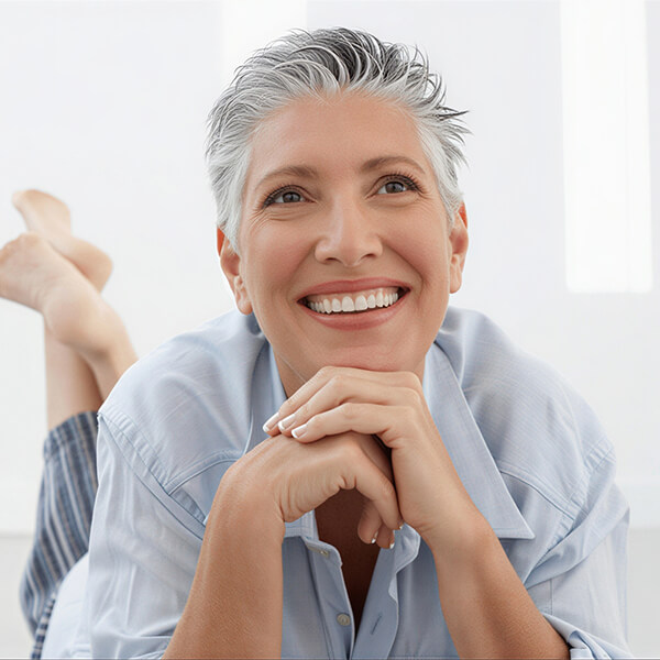 A woman with short hair smiling while laying down